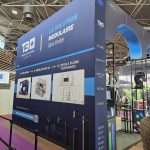 Illuminated exhibition wall showcasing modular display systems and branding at C!Print Lyon