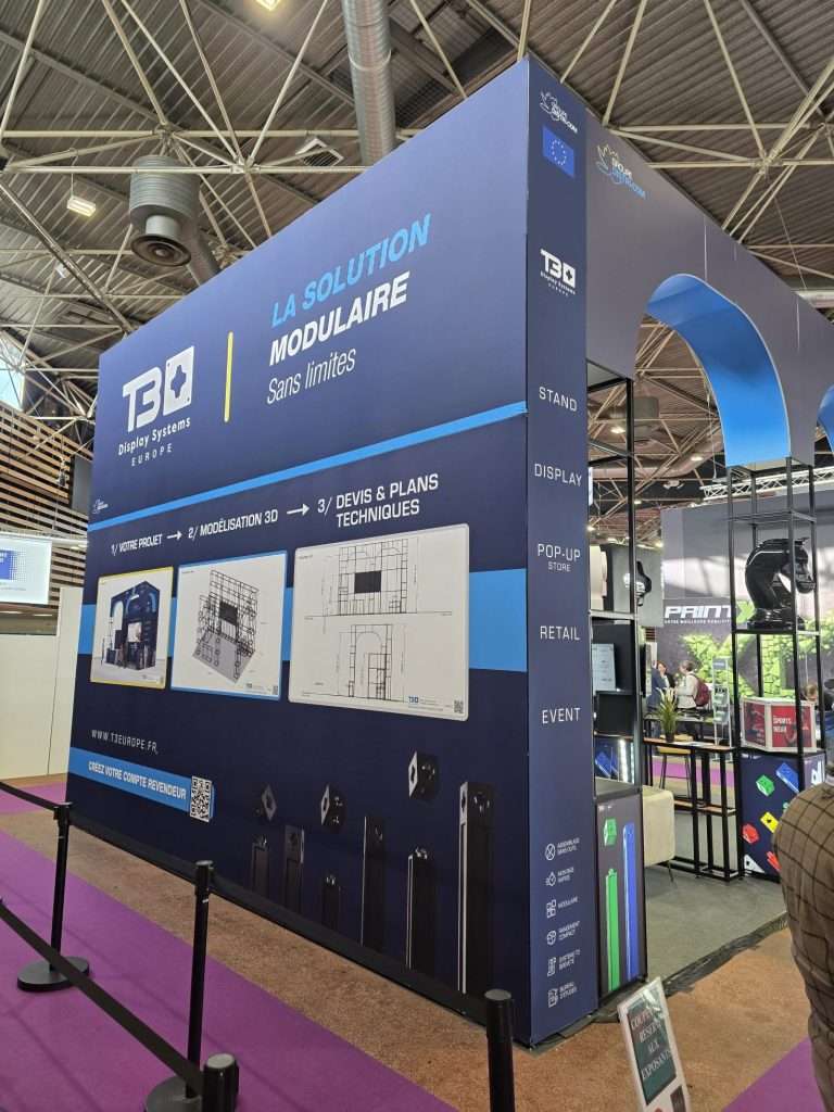 Illuminated exhibition wall showcasing modular display systems and branding at C!Print Lyon