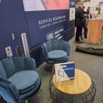 Exhibition stand seating area featuring curved design, soft furnishings, and branded panels at C!Print Lyon